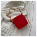 Red matte leather chain bag with golden metal strap on a white blazer background - Red