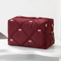 Macro detail of wine red quilted cosmetic bag with white bow embroidery and metal zipper - Angola Red