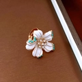 Dettaglio macro di spilla floreale vintage in smalto bianco con strass e placcatura oro - Anello