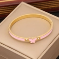 Dettaglio macro del motivo farfalla in smalto rosa su bracciale rigido in oro e zirconi - Rosa