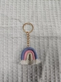 Detailed macro view of handmade woven rainbow keychain with cotton tassels and gold ring - Dark Violet