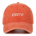 Close-up of white ESKETIT letter embroidery on a washed orange cotton baseball cap - Orange