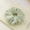 Primo piano di un morbido elastico per capelli in peluche verde chiaro su un libro - Pelliccia sintetica verde