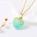 Vue macro d'un pendentif cœur doré serti de cristaux scintillants vert et bleu clair - Dégradé Vert Bleu