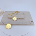 Detail of gold-plated pendant with crescent moon zircon inlay on beige stone texture - White Shell Moon Star