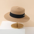 Detail of hand-woven straw hat featuring black ribbon band and metal logo plaque - Khaki