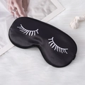 Black satin sleep eye mask with white eyelash print on soft white plush background - Black
