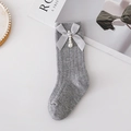 Dettaglio di calze grigie a maglia con fiocco in raso e ciondolo di perla su fondo bianco - XS (0-1 Anni) / Grigio