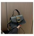 Detail of black PU leather handbag with golden metal buckles and handle held by hand - Black