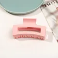 Detail of matte pink rectangular hair claw clip on a white table with a blue plate - 8.5cm Rectangular - Matte Girly Pink