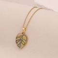 Macro shot of gold-plated leaf pendant with colorful enamel and sparkling rhinestones - Green