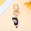 Cute black and white enamel cat keychain with gold metal spring buckle on yellow background - Black Cat