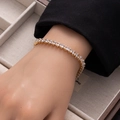 Close-up of a golden tennis bracelet with princess cut zircons on a model wrist - Gold 5*4 Rectangle