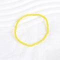 Detail of vibrant yellow seed bead elastic bracelet on textured white background - Bright Yellow