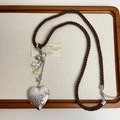 Dettaglio collana con medaglione a cuore vintage, ciondoli marini e corda intrecciata - Scatola a Cuore Incisa-Cordino Intrecciato Marrone
