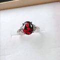 Close-up van een ovale rode granaat ring met hol bladontwerp en zilveren details - Verstelbaar Open / Witgoud