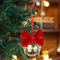Red velvet bow with golden metal bell ornament hanging on a lush green Christmas tree - Red Bowtie Style