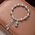 Macro shot of silver beaded bracelet featuring carved square charm and lotus pendants - Buddha Peace