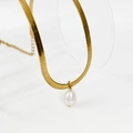 Detail einer goldenen flachen Schlangenkette mit weißem Perlenanhänger in Tropfenform - Gold