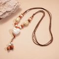 Detail van een wit keramisch hartvormig hangertje aan een kralenketting met natuursteen - Wit