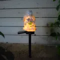 Close-up of solar resin angel statue with warm yellow glow and pink flower details - Bouquet Angel