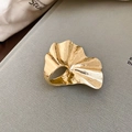 Macro di anello a foglia di ginkgo dorata con venature dettagliate su sfondo di tessuto - Oro