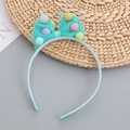 Light blue girls headband with mesh bow and colorful pom-poms shown on grey surface - Green Headband / Green