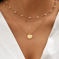 Three-layer gold necklace with pearls and circular pendant on a white V-neck top - Style 02 / Gold