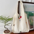Detailed view of floral embroidery on a cream canvas tote bag in a cozy home setting - Beige Green Leaf Flower