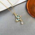 Elegant gold butterfly necklace with blue zircon stones on textured gray background - Butterfly Zircon-Gold 0371JL