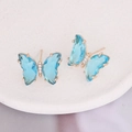Light blue butterfly earrings with white cubic zirconia and gold plating on a tray - Lake Blue