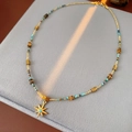 Detalle de collar de cuentas con colgante de estrella y gema azul en terciopelo - Estilo de Cuentas Multicolor con Estrella de Ocho Puntas Dorada