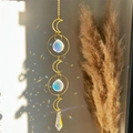 Golden moon suncatcher with clear crystals casting colorful light on a neutral wall - Triple Crescent Moon Prism Style