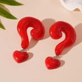 Detailed view of red resin question mark and heart dangle earrings on a beige surface - Red