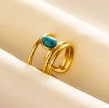 Macro view of gold tiered ring featuring a hammer textured finish and teardrop turquoise stone - Gold - Dark Blue Faux Stone