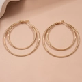 Detail view of double layer gold geometric hoop earrings on a light pink background - Gold