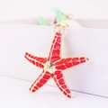 Detailed view of red starfish charm with gold edges and colorful enamel finish - Red