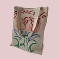 Detailed close-up of beige knitted tote bag with colorful floral embroidery and text - Beige Rose Floral