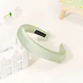 Close-up of mint green padded headband featuring handmade label and silky satin texture - Light Green