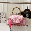 Rosa Brokat-Handtasche mit Bambusgriff und goldenem Quastenanhänger im Fotostudio - Rosa