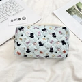 Detail of light blue quilted pouch with black cat patterns on a soft white surface - Black Cat Dots