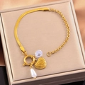 Detail of gold snake chain bracelet with heart, pearl and gemstone charms in a jewelry box - Heart