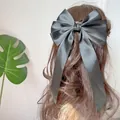 Oversized black satin bow hair clip with long ribbons worn on the back of long hair - Black