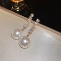 Detailed close-up of a gold pearl drop earring with zircon stones in a velvet box - 11# Gold Pearl