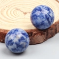 Polished natural blue sodalite crystal spheres displayed on a rustic wood slice background - Sodalite