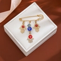 Gold Hamsa Hand brooch with red and blue evil eye charms and rhinestones on jewelry box - Hamsa Multi-Pendant Style (Z107-1)