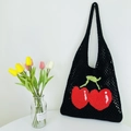 Detail of black knitted mesh tote bag featuring iconic red cherry pattern and woven texture - Black
