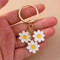 Daisy flower keychain with white enamel petals and gold plating on a pink background - White