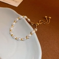 Detail of beaded pearl bracelet with gold adjustable drawstring on ceramic tray - Gold Pearl Bracelet