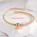 Gold stainless steel twisted cable open bangle with spherical centerpiece and ribbed ends - Cable Gold Beads